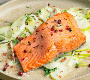 A photo of a fillet of salmon on a bed of vegetables a meal that can contribute to senior fitness