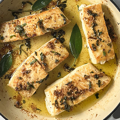 Halibut fillets in a pan with brown butter and sage