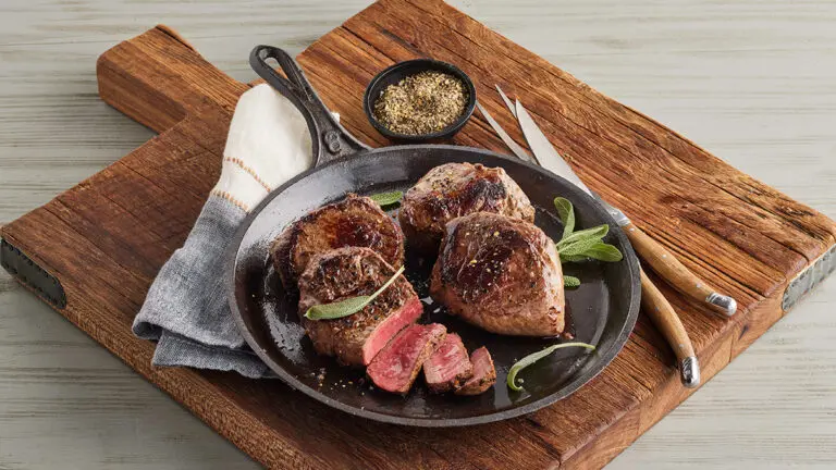 Frying pan with several sirloin steaks.